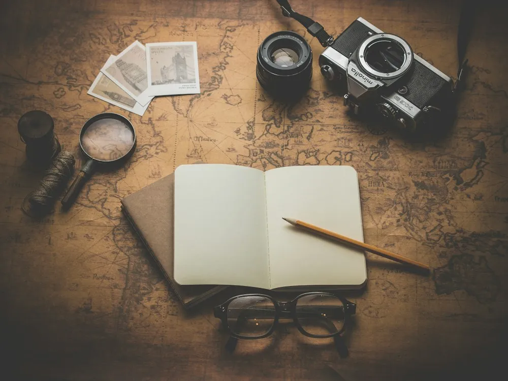 An old map with a camera, a notebook, glasses and a magnifying glass.