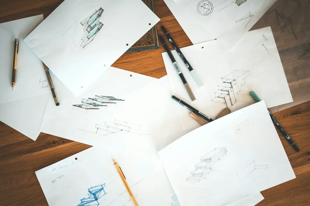 Loose pencil sketches of a product scattered on a wooden table.